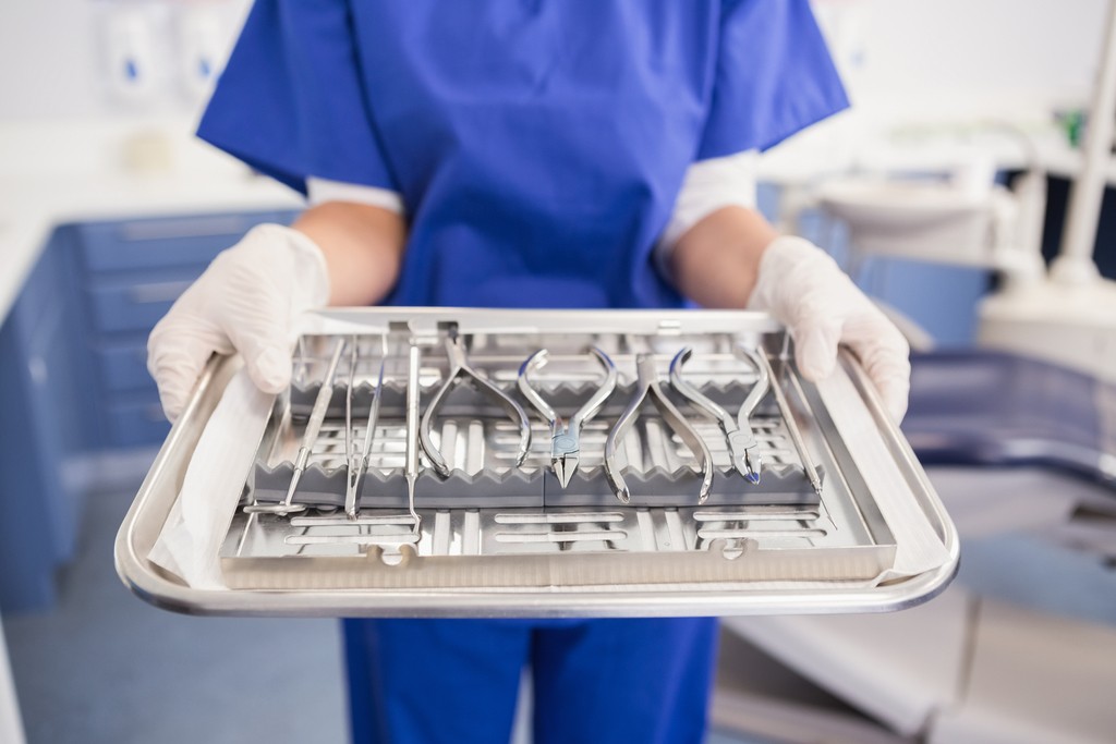 Dentist holding tray with equipment in dental clinic