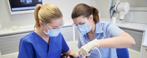 dentist and dental assistant do dental work on a patient
