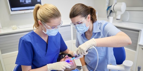 dentist and dental assistant do dental work on a patient