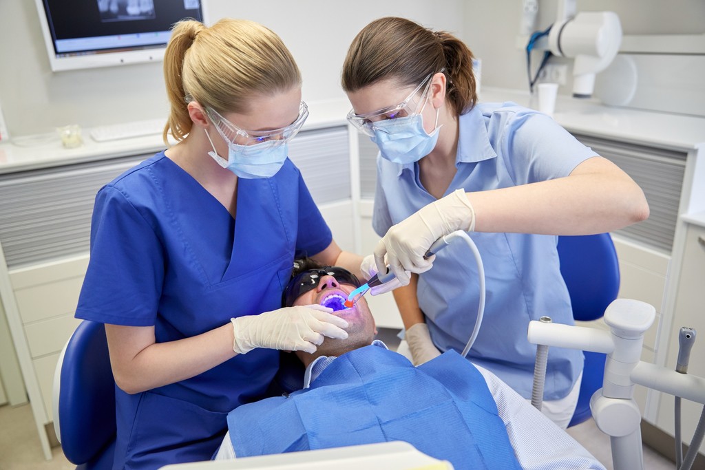 dentist and dental assistant do dental work on a patient