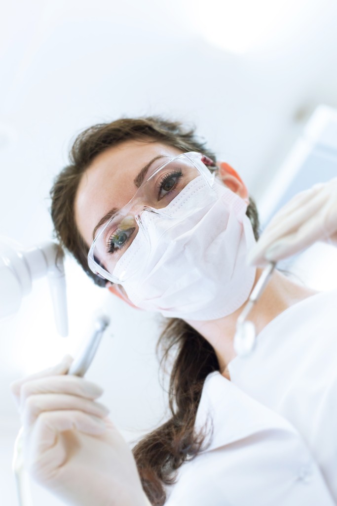 Dentist In Mask Holding Angled Mirror And Drill